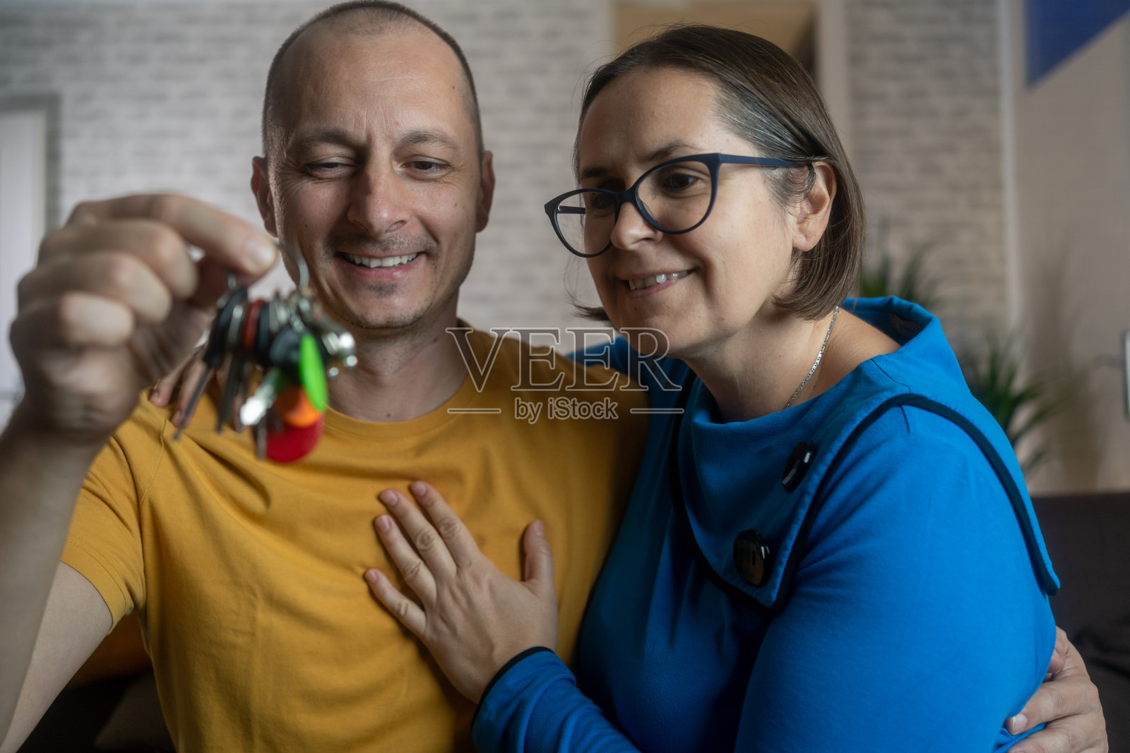 一对幸福的夫妇买了房子，微笑着拿着钥匙照片摄影图片