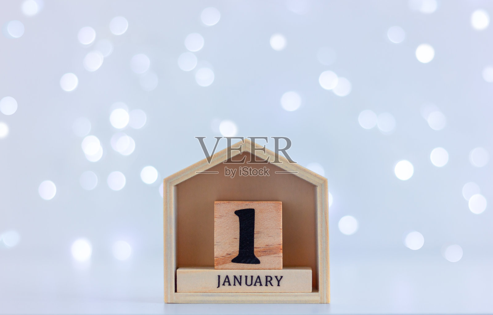 以节日彩灯为背景，日期为1月1日的木制日历。概念庆祝，寒假，新年。照片摄影图片