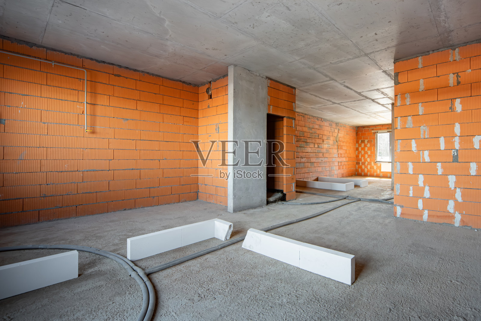 住宅公寓的内部结构是在建造新房子的过程中形成的。墙是红砖砌的。空旷的现代明亮房间照片摄影图片