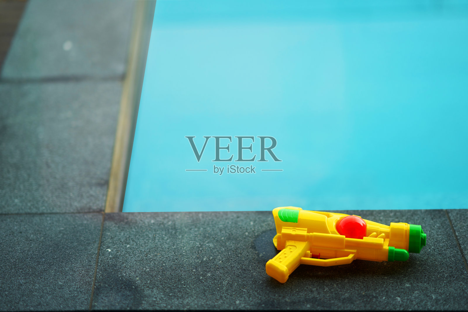 夏季泰国节日概念中蓝水游泳池池边的水枪与复制空间照片摄影图片