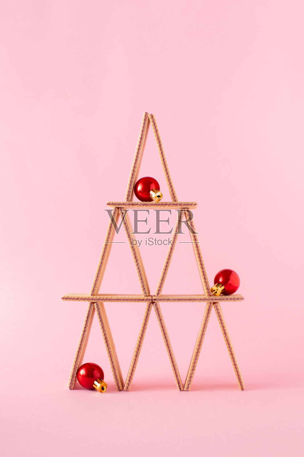 在淡粉色的背景上，用华夫饼干装饰成圣诞树的形状。圣诞树概念。照片摄影图片