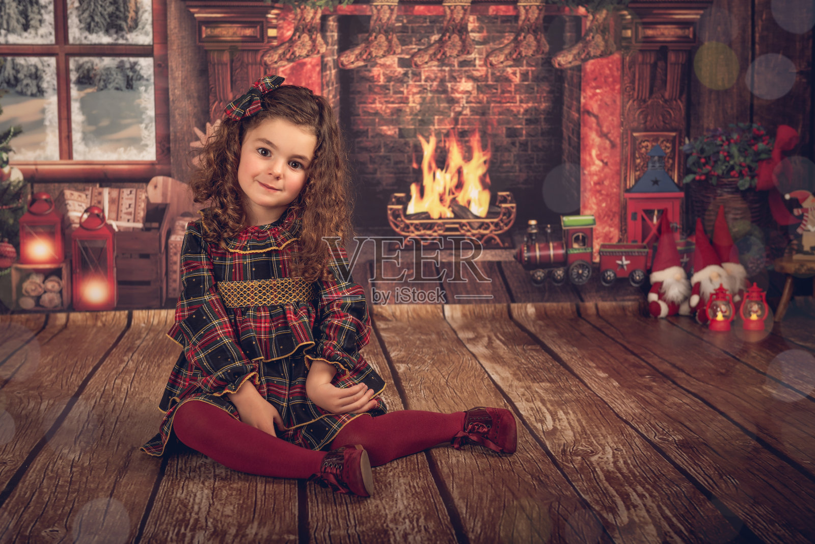 一个穿着圣诞装饰的女孩，坐在地板上看着镜头。照片摄影图片