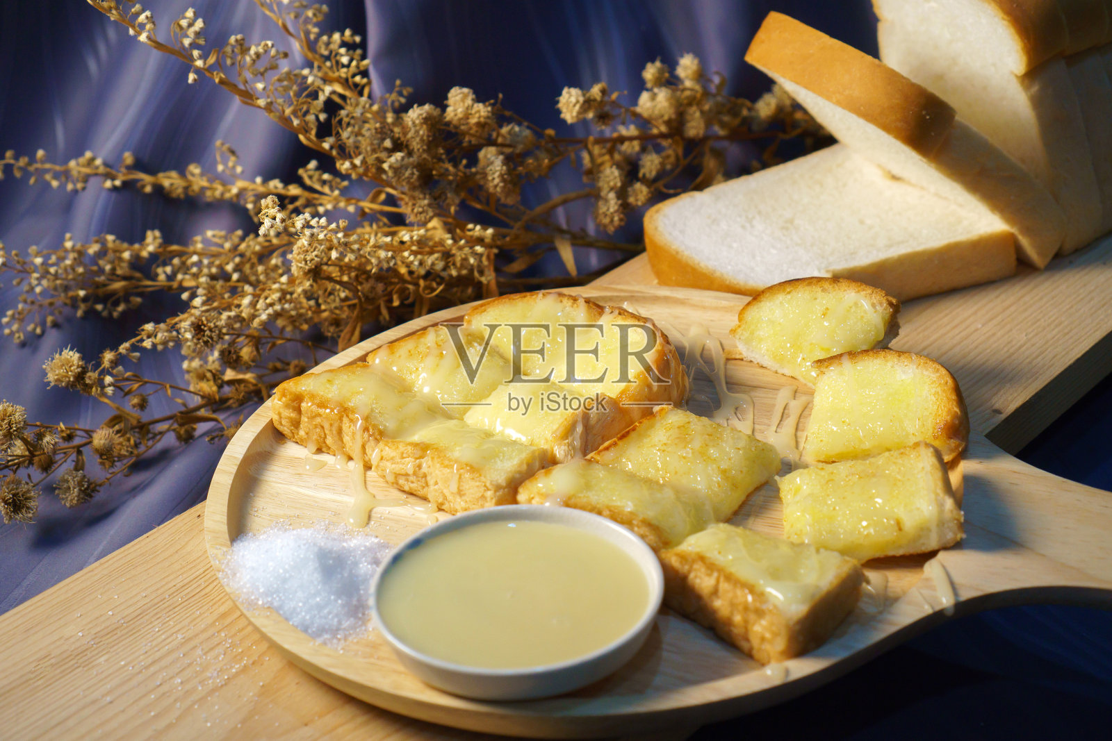 用木盘烤面包，涂上黄油和蜂蜜照片摄影图片