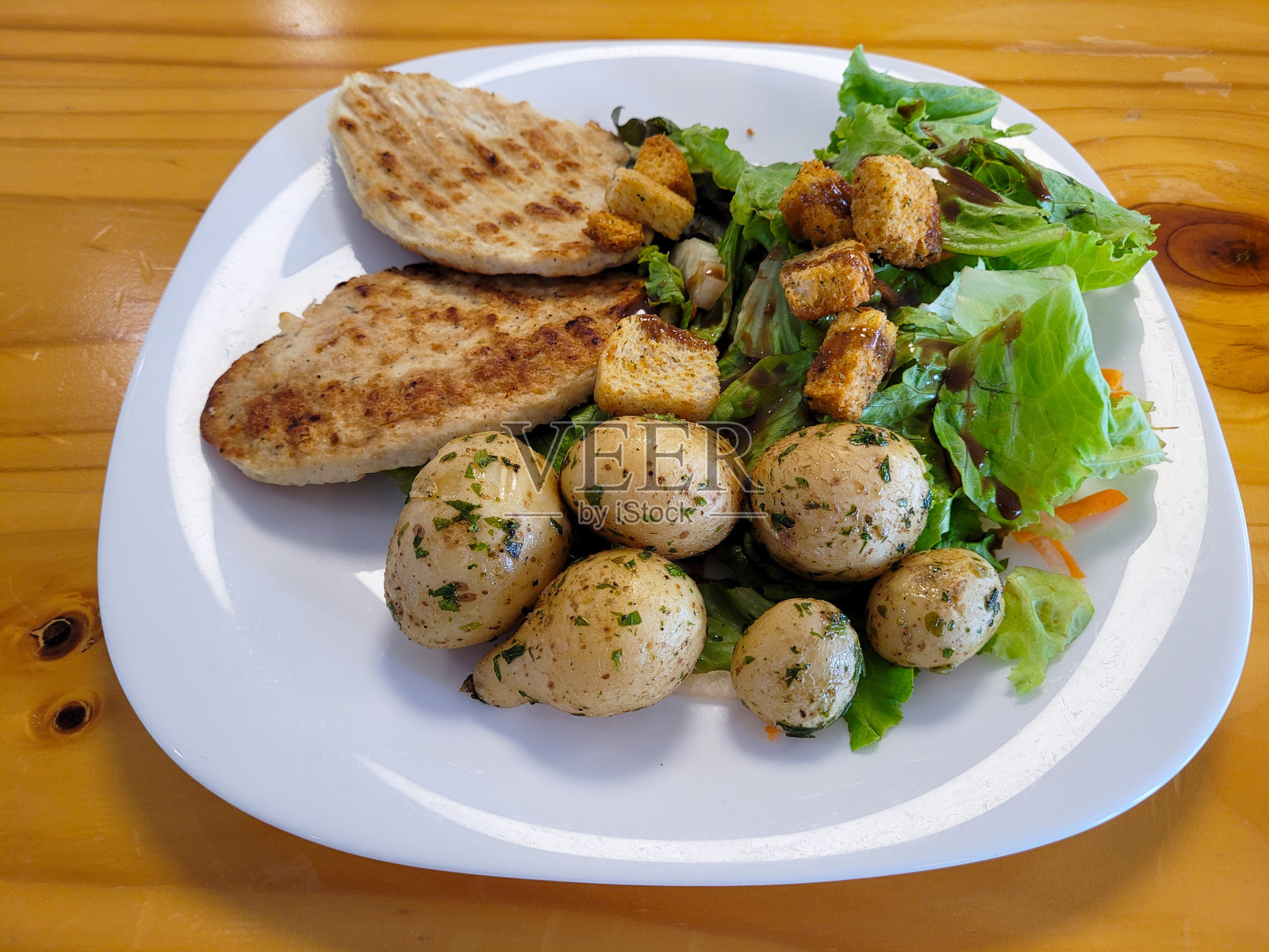 木桌上的烤鸡胸肉配沙拉和马铃薯照片摄影图片