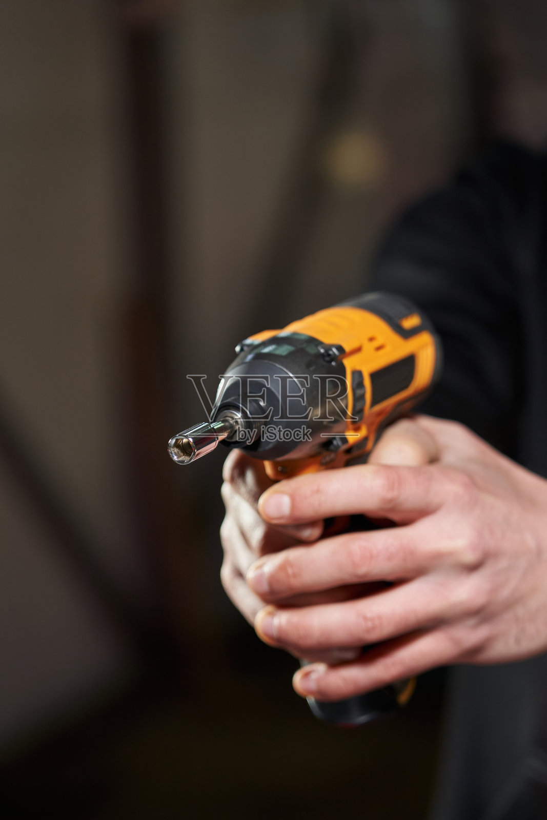 两个人的手紧紧握住带小螺母附件的电动无绳冲击扳手照片摄影图片