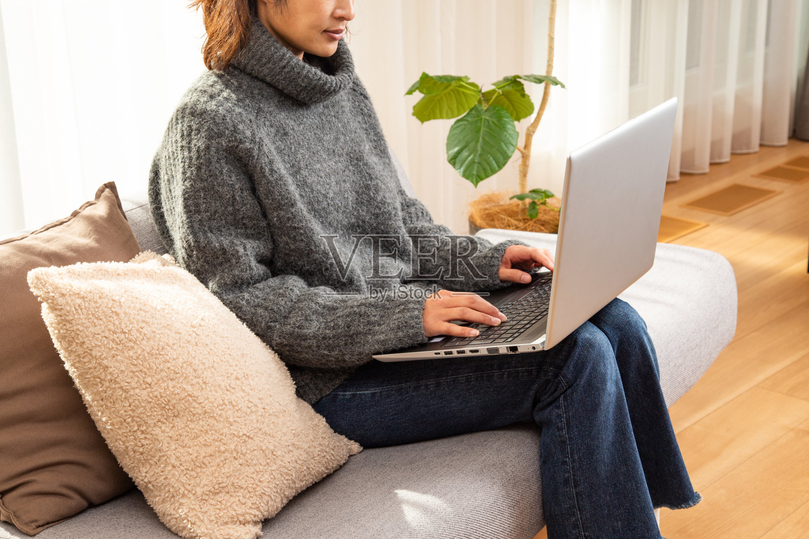 一个女人在客厅里用笔记本电脑。照片摄影图片