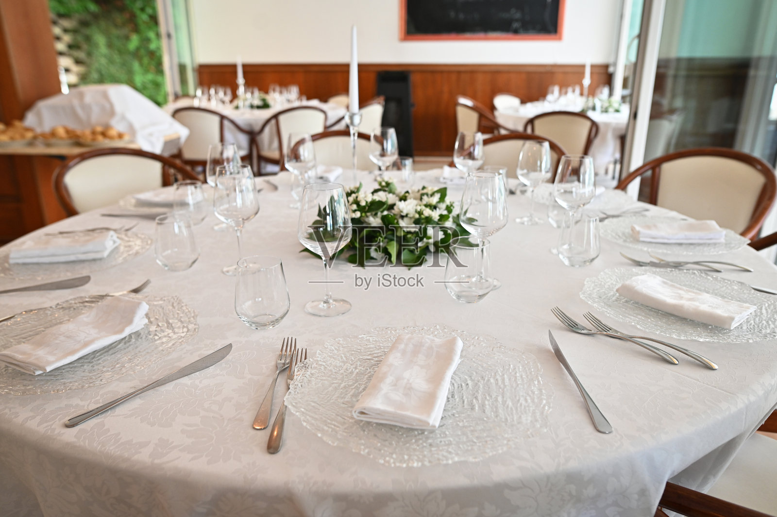 宴会桌上装饰着盘子、餐具、玻璃杯、插花照片摄影图片