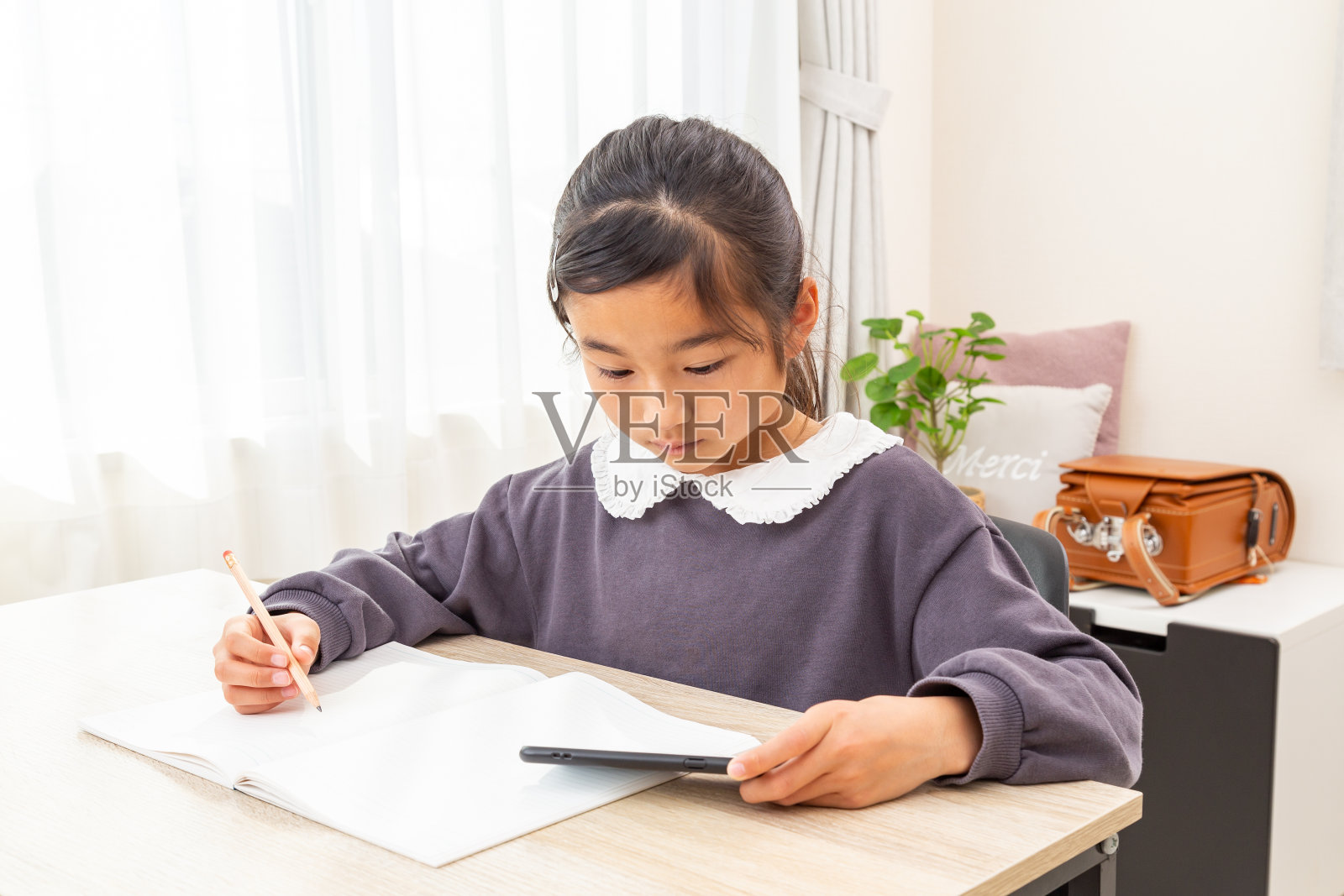 一个女孩用智能手机学习。照片摄影图片