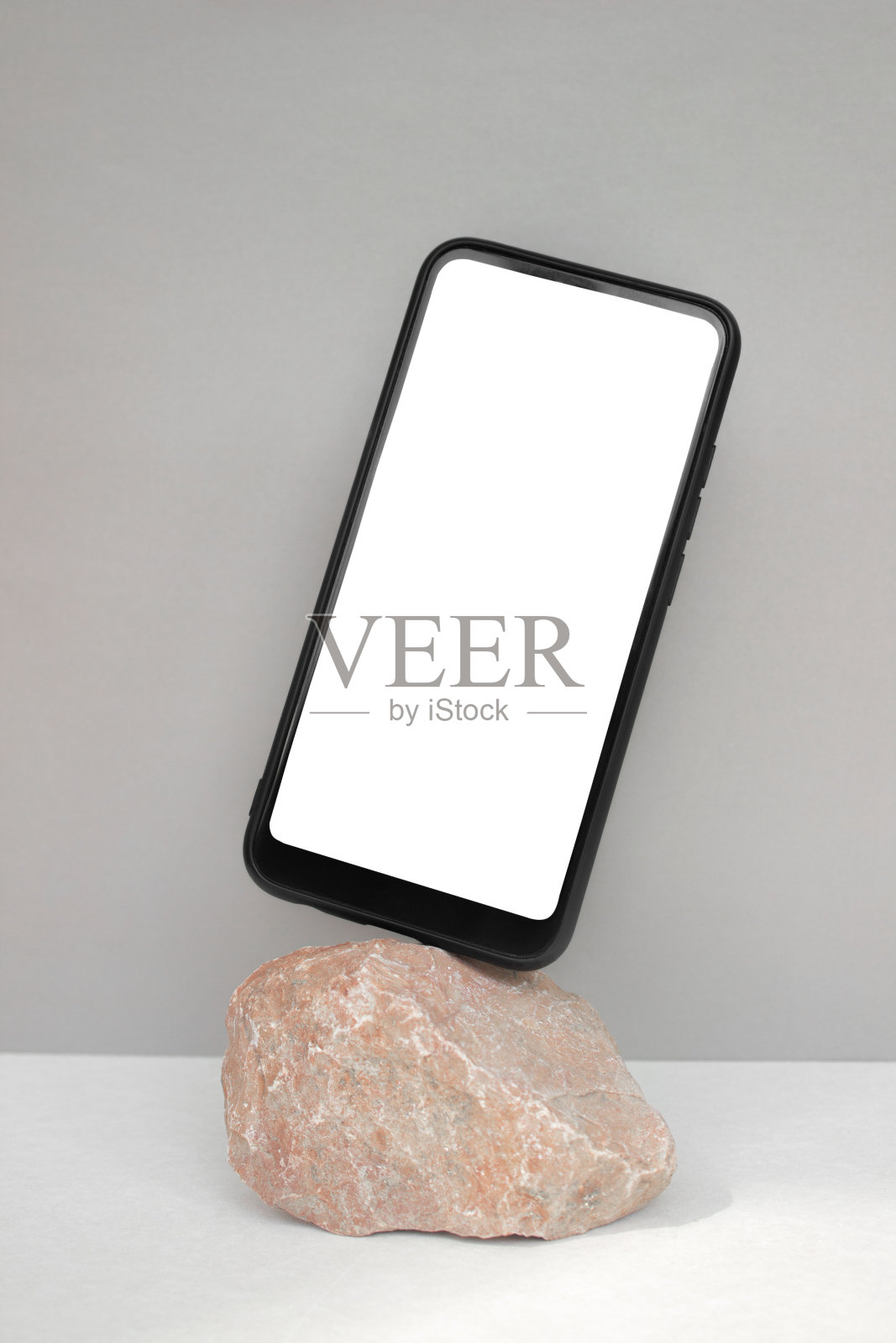 灰色背景上的天然红色石头上的智能手机模板。极简主义的风格。垂直图照片摄影图片