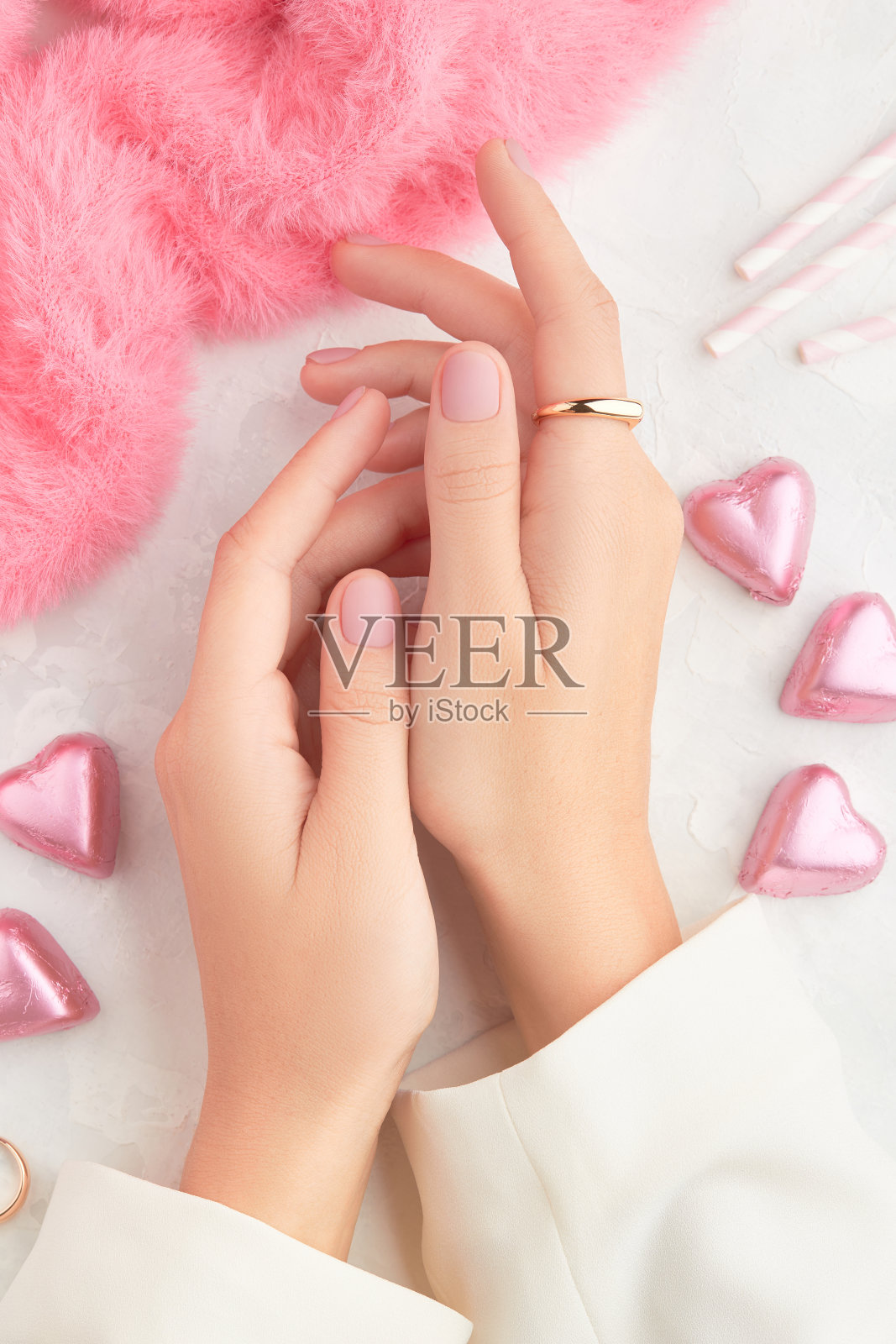 美丽的修饰女人的手与粉红色哑光指甲设计在粉红色的背景。美甲、足疗美容院照片摄影图片