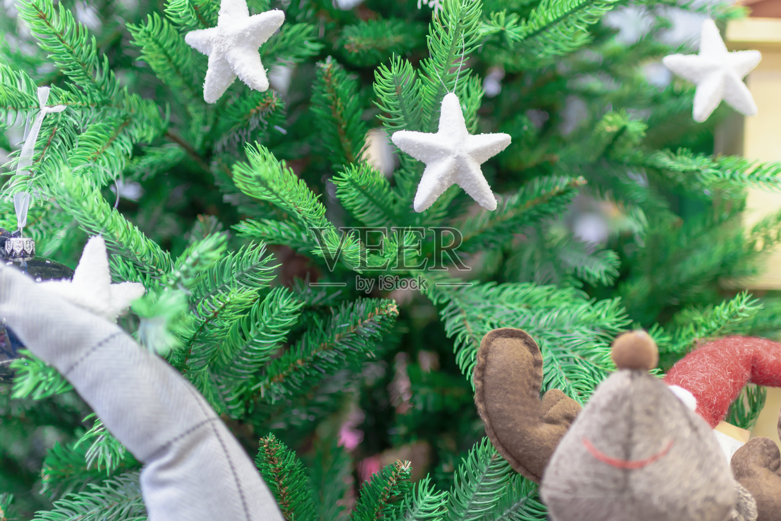 新年的玩具球和星星、雪花以绿色的圣诞树为背景。概念软玩具。关闭了。照片摄影图片
