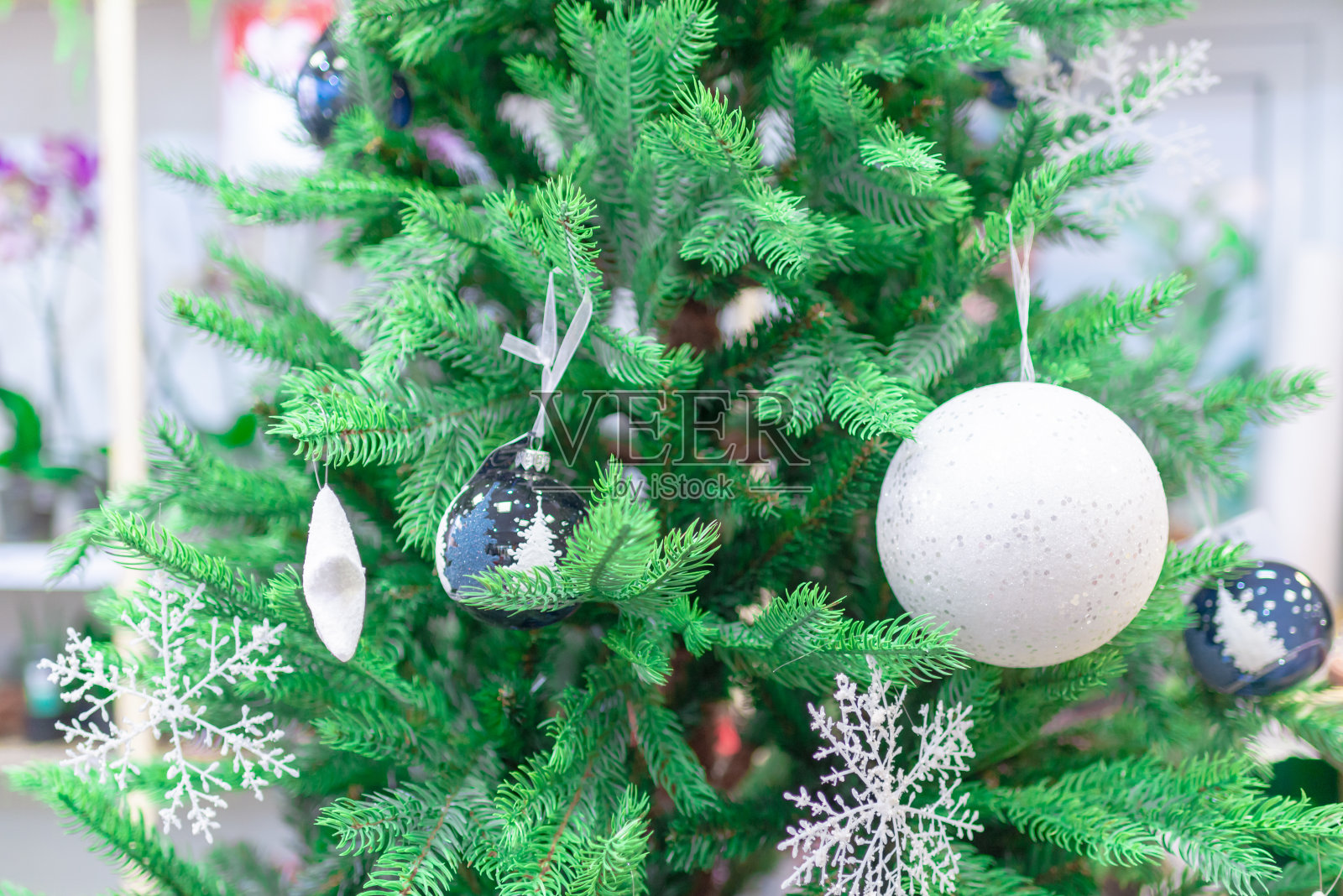 近距离的圣诞树装饰，白色的球，闪闪发光的球和雪花星。照片摄影图片