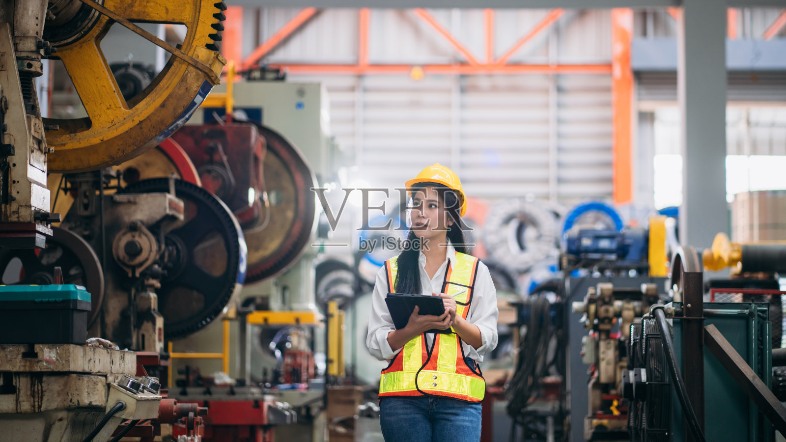 工业工人在工厂机器前用压片机检查。在钣金公司工作的技术员。照片摄影图片