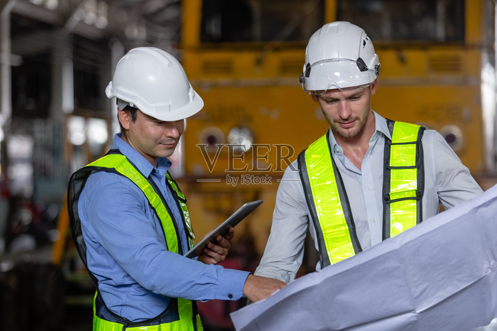 带领铁路工程师带着图纸到维修中心检查检修项目列车柴油机。技术员讨论计划检查车辆和铁路系统。照片摄影图片