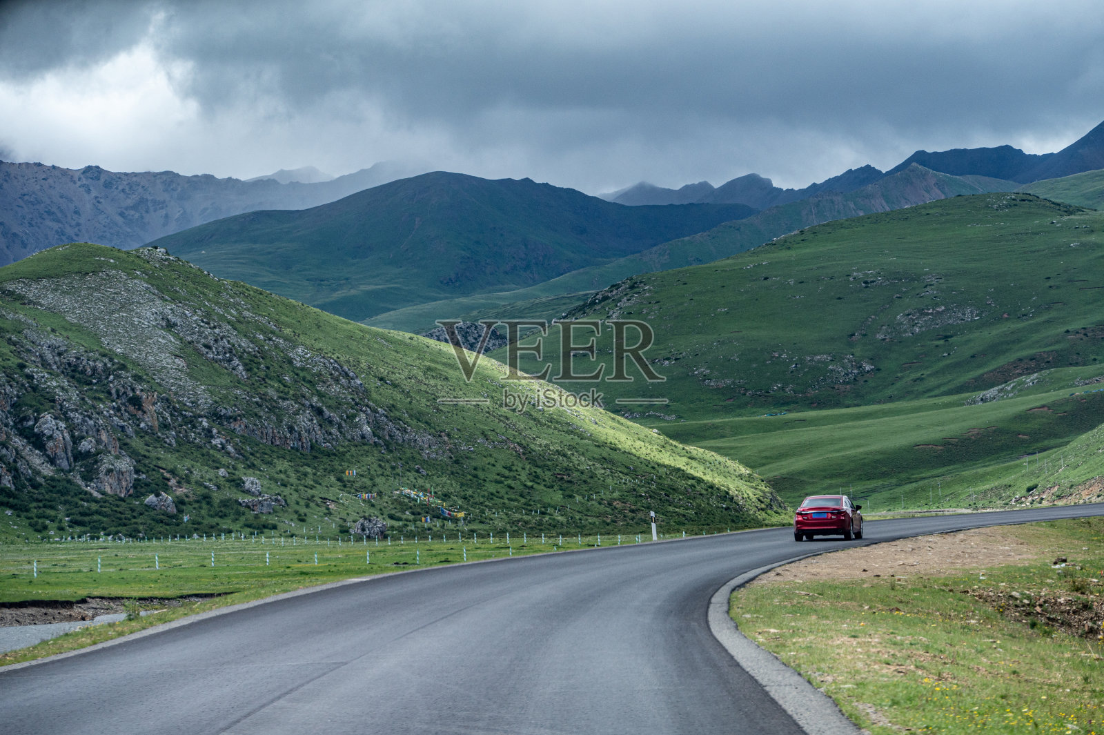 多云天气下高原草地上的道路照片摄影图片