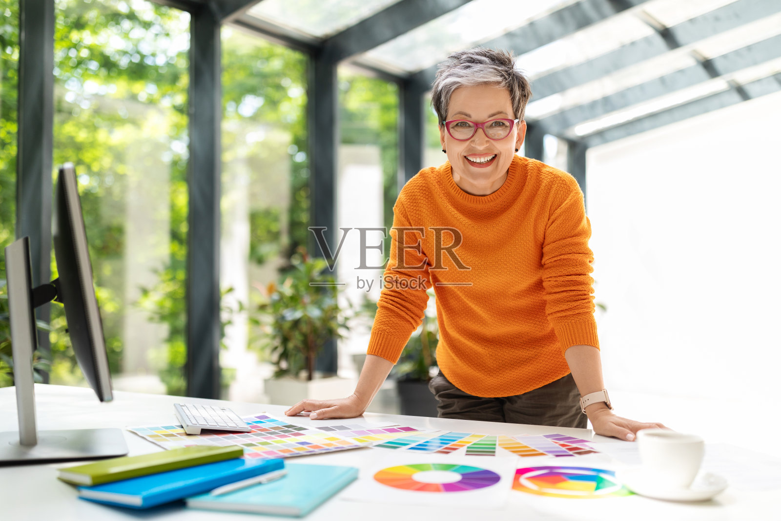 在办公室工作的开朗成熟的女设计师照片摄影图片