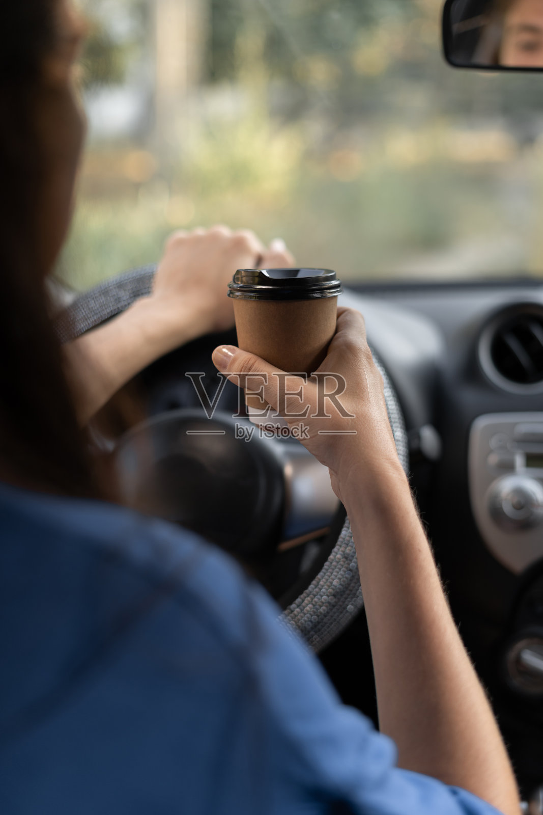 拿着纸杯咖啡的女子在室内开车。咖啡休息时间概念照片摄影图片