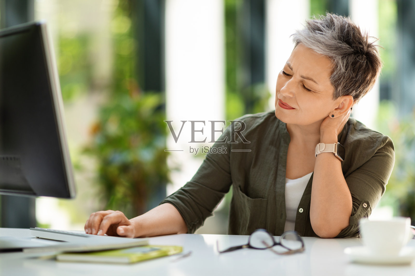 高加索成熟的商人坐在工作场所，忍受着脖子痛照片摄影图片