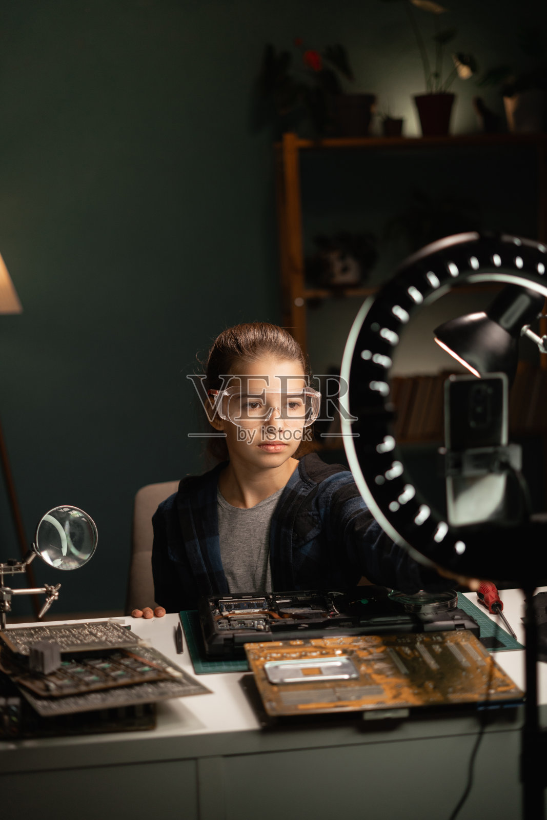 十几岁的女孩用智能手机和戒指灯为社交媒体制作视频内容。博主谈论在智能手机屏幕上修理笔记本电脑。使广播与关注者沟通照片摄影图片
