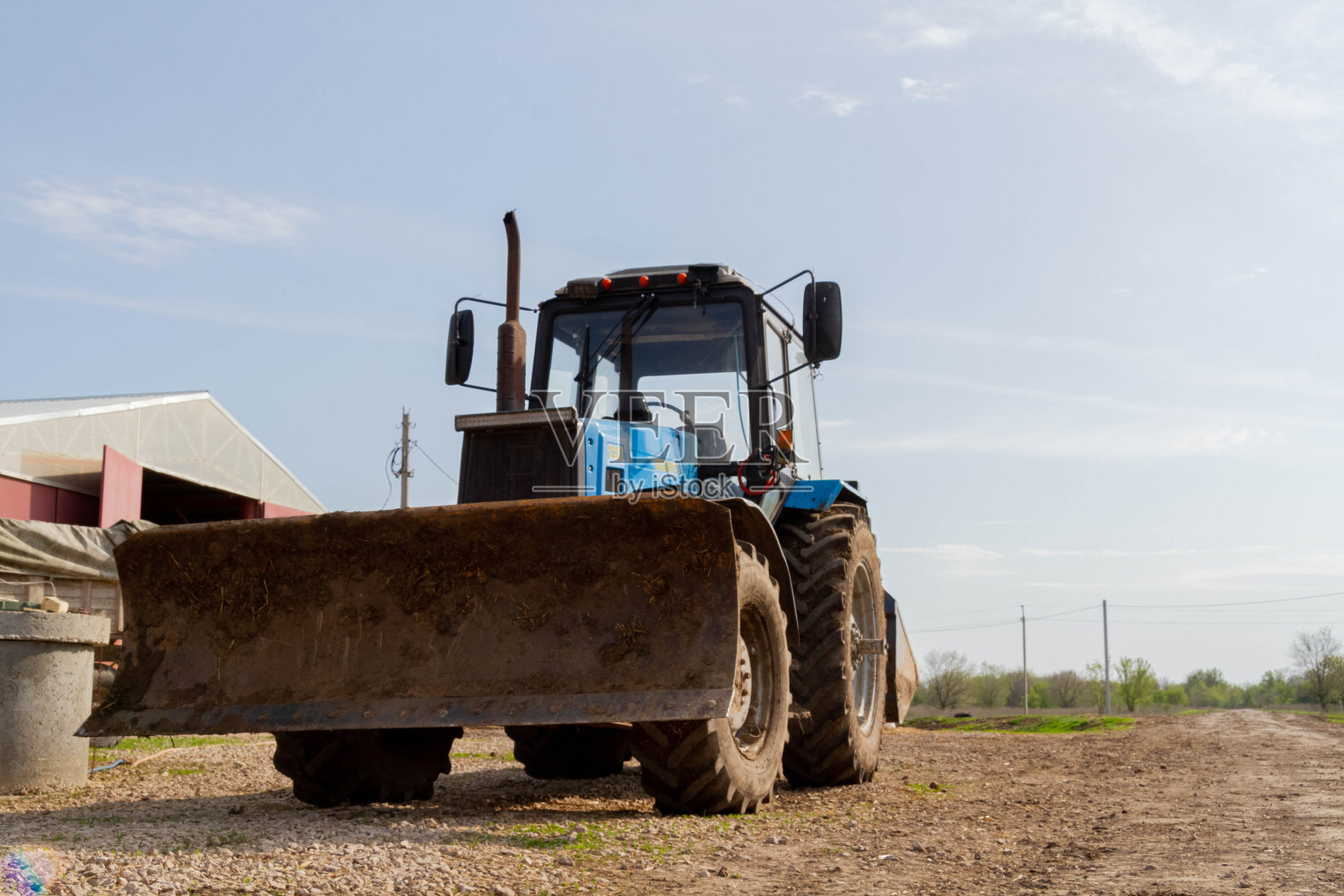 农场上的拖拉机。农民的设备。蓝色拖拉机映衬着村庄的背景。照片摄影图片