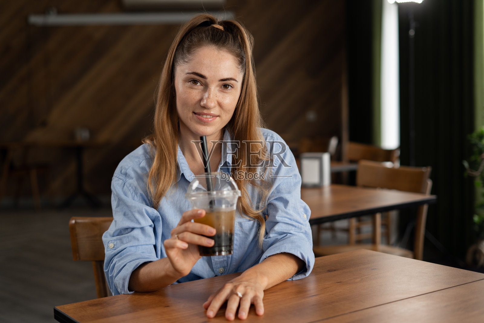年轻女子在餐馆或咖啡馆看着镜头，愉快地喝着泡泡茶照片摄影图片