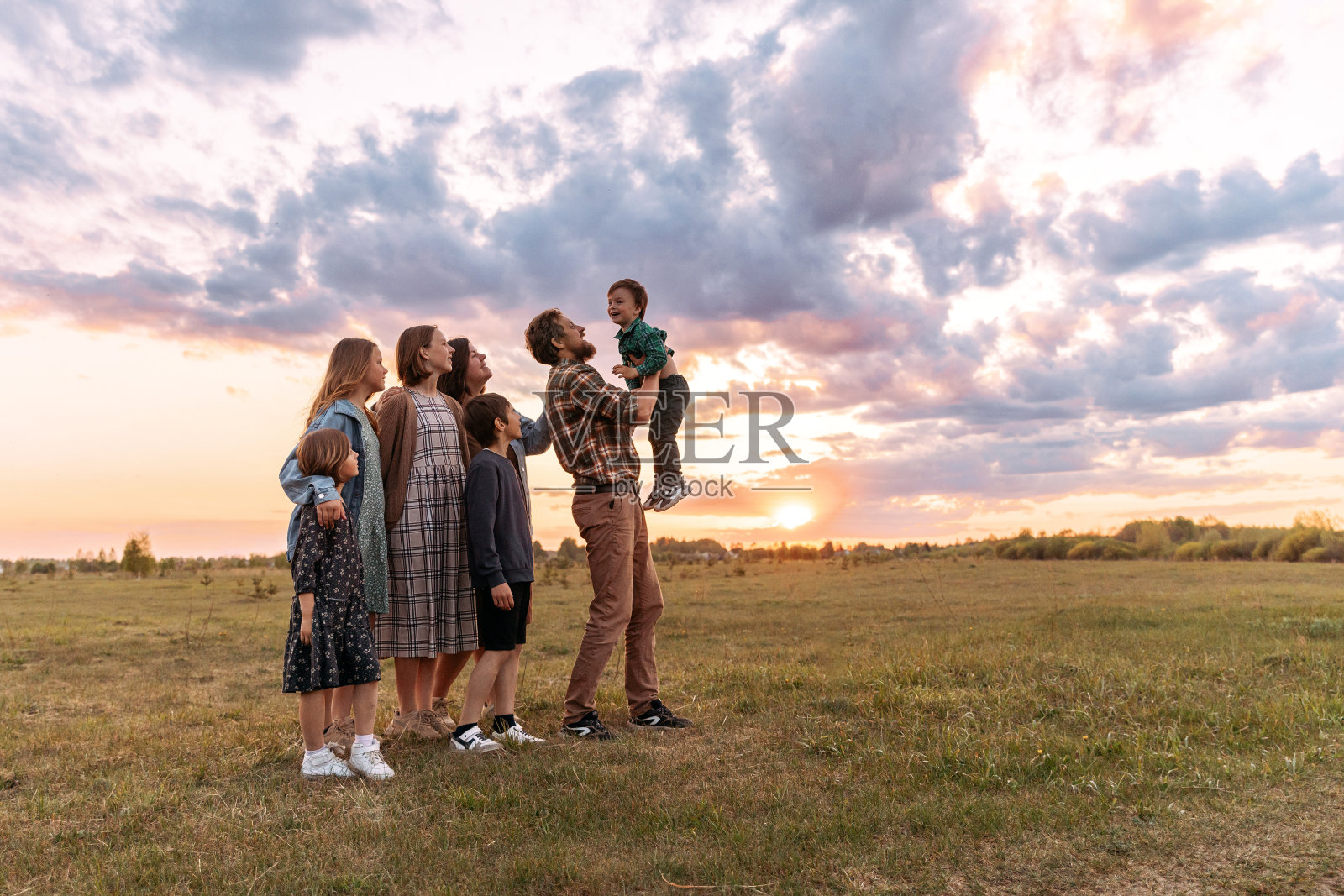 夏天，一个快乐的大家庭在田野里散步。照片摄影图片