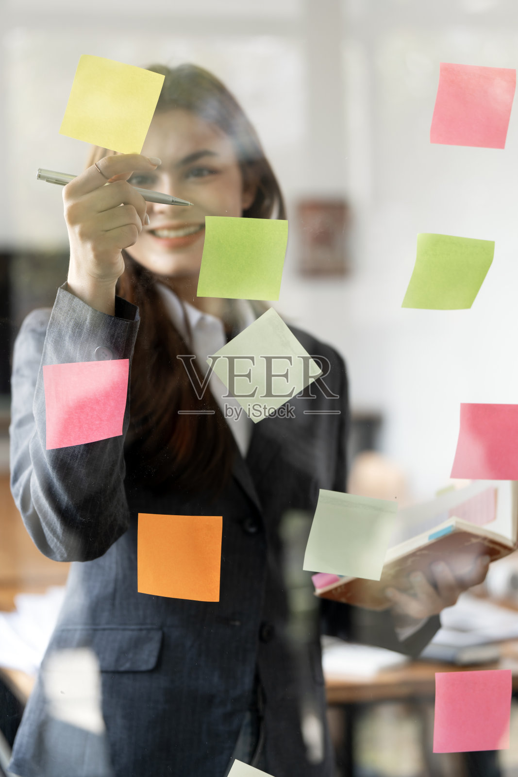 年轻的微笑有吸引力的女商人使用便利贴在玻璃墙写战略商业计划发展成长到成功照片摄影图片