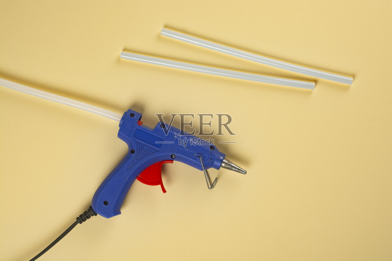 蓝色胶枪和胶贴在黄色背景上，平铺照片摄影图片