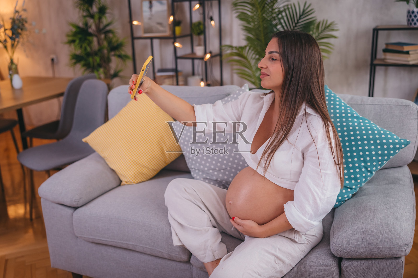 一个怀孕的漂亮女人用她的智能手机打视频电话照片摄影图片