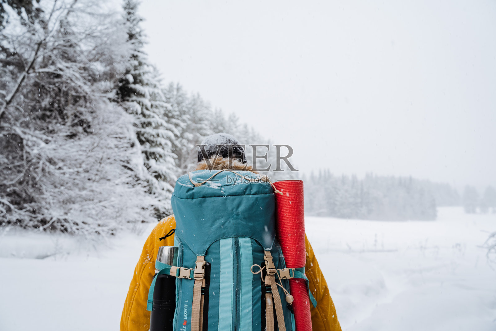 旅行者背上徒步背包的近照。白雪皑皑的森林和岩石。冬天爬山。野外生存。照片摄影图片