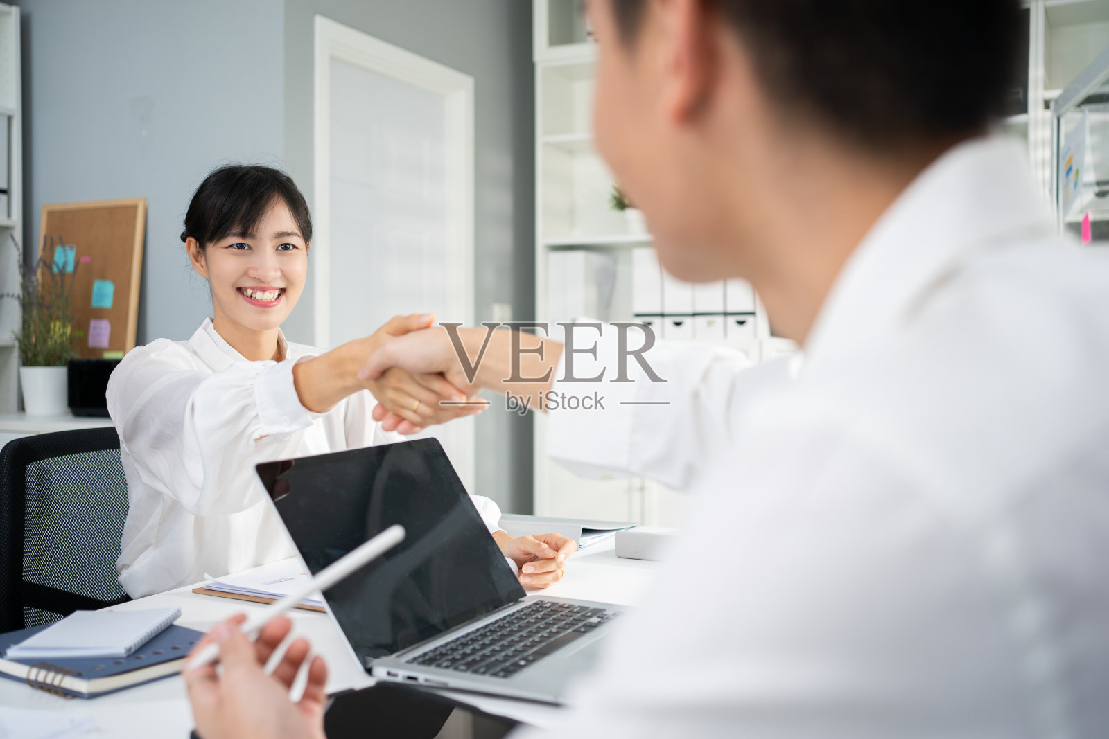 年轻的亚洲商人在办公室里握手。握手，圆满结束会议。感谢您的参与。照片摄影图片