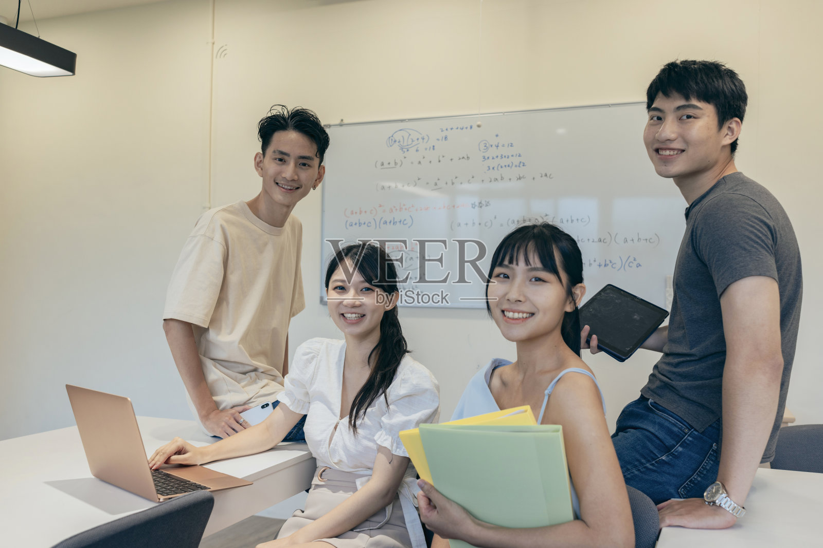 在教室里，学生们看着镜头，微笑着。他们可能坐在办公桌前，表现出友好和快乐的表情。这种氛围反映了学习环境中快乐和友爱的时刻。照片摄影图片