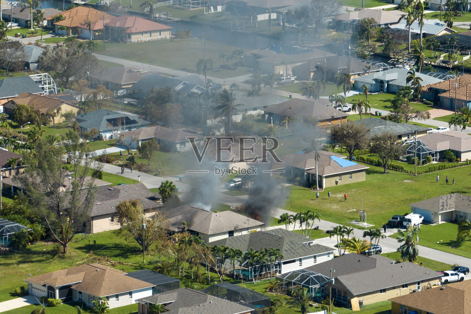 燃烧的住宅着火，烟雾和火焰，消防员在短路火花点燃被飓风伊恩损坏的木制屋顶后将其扑灭。佛罗里达农村地区发生家庭灾难照片摄影图片