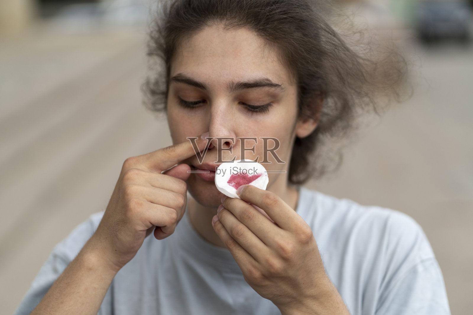 一名男子捂着流着血的鼻子，拿着白色的棉垫照片摄影图片