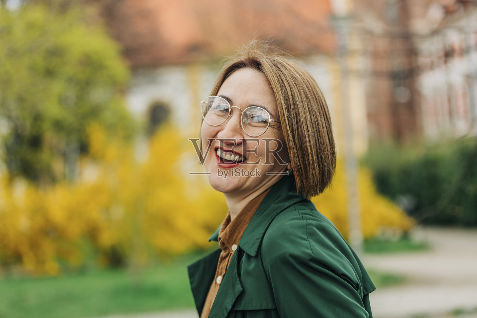 在波兰弗罗茨瓦夫的城市街道上，一位穿着绿色外套、面带微笑的50岁时髦妇女照片摄影图片