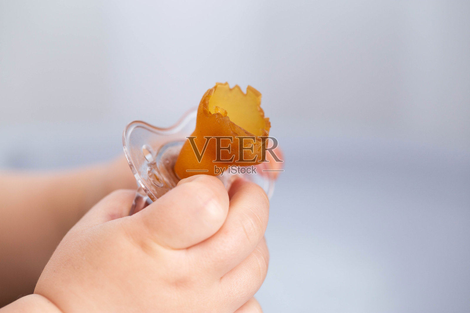 婴儿手中被咬破的硅胶乳头。儿童咬伤问题的概念是由于安抚奶嘴。初期,儿科。文本复制空间照片摄影图片