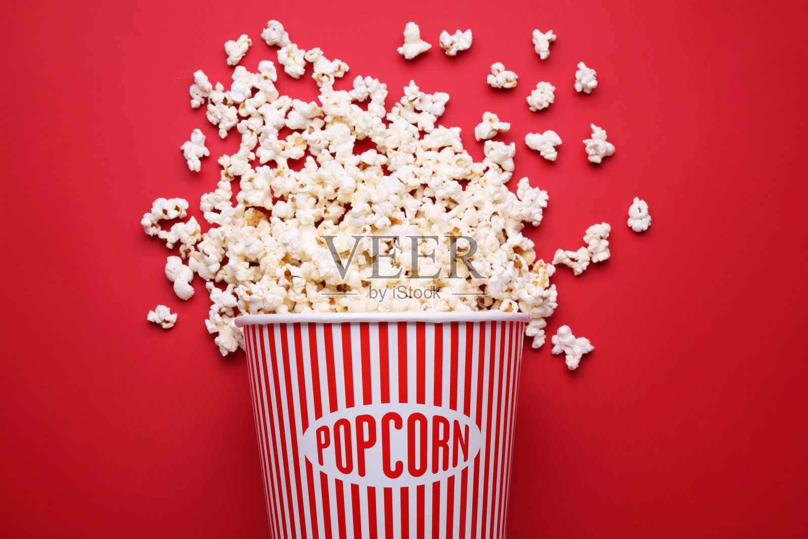 翻倒的纸桶，红底装着美味的爆米花，平躺着照片摄影图片