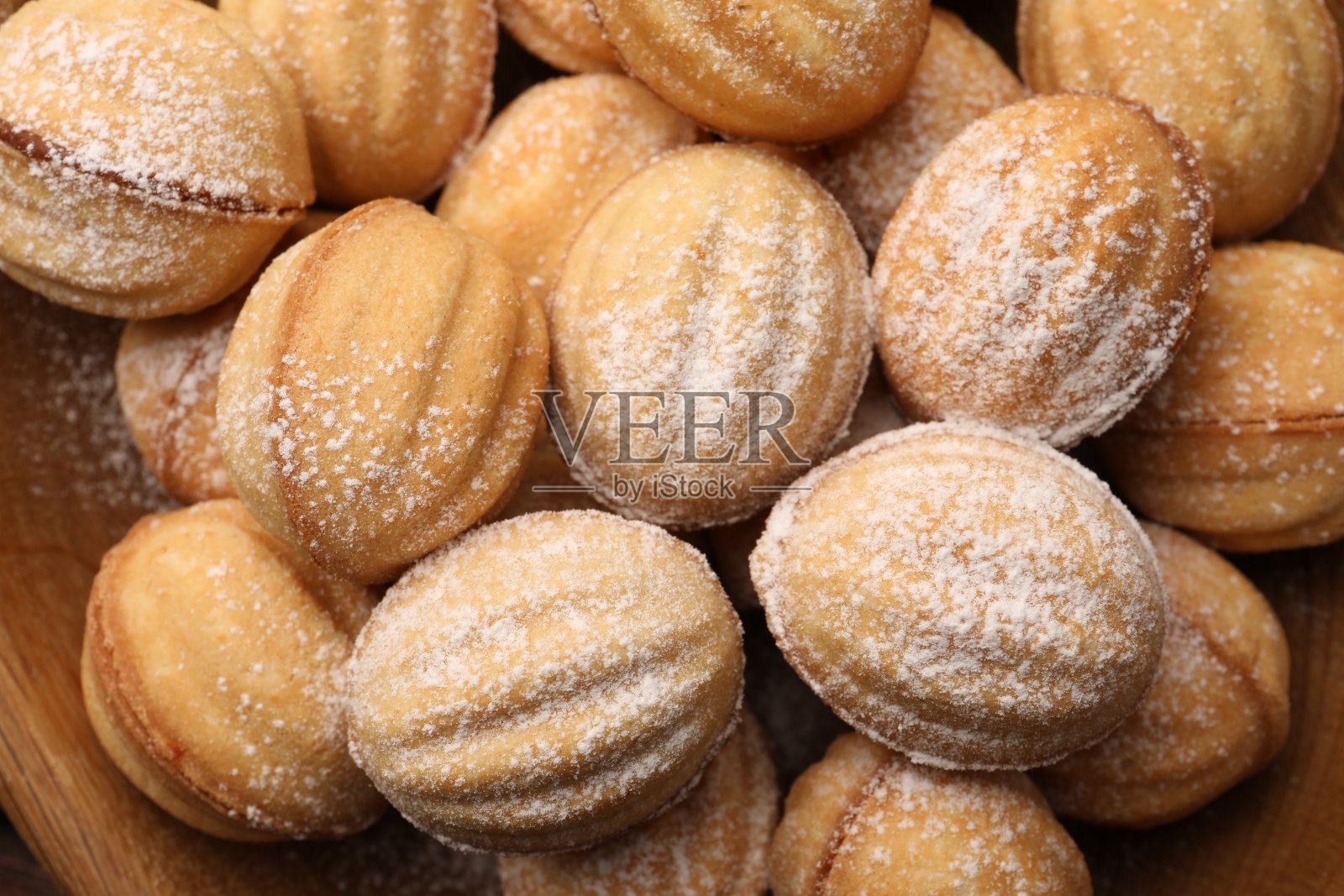 美味的坚果形状的饼干，煮炼乳和糖粉在木桌上，俯视图照片摄影图片