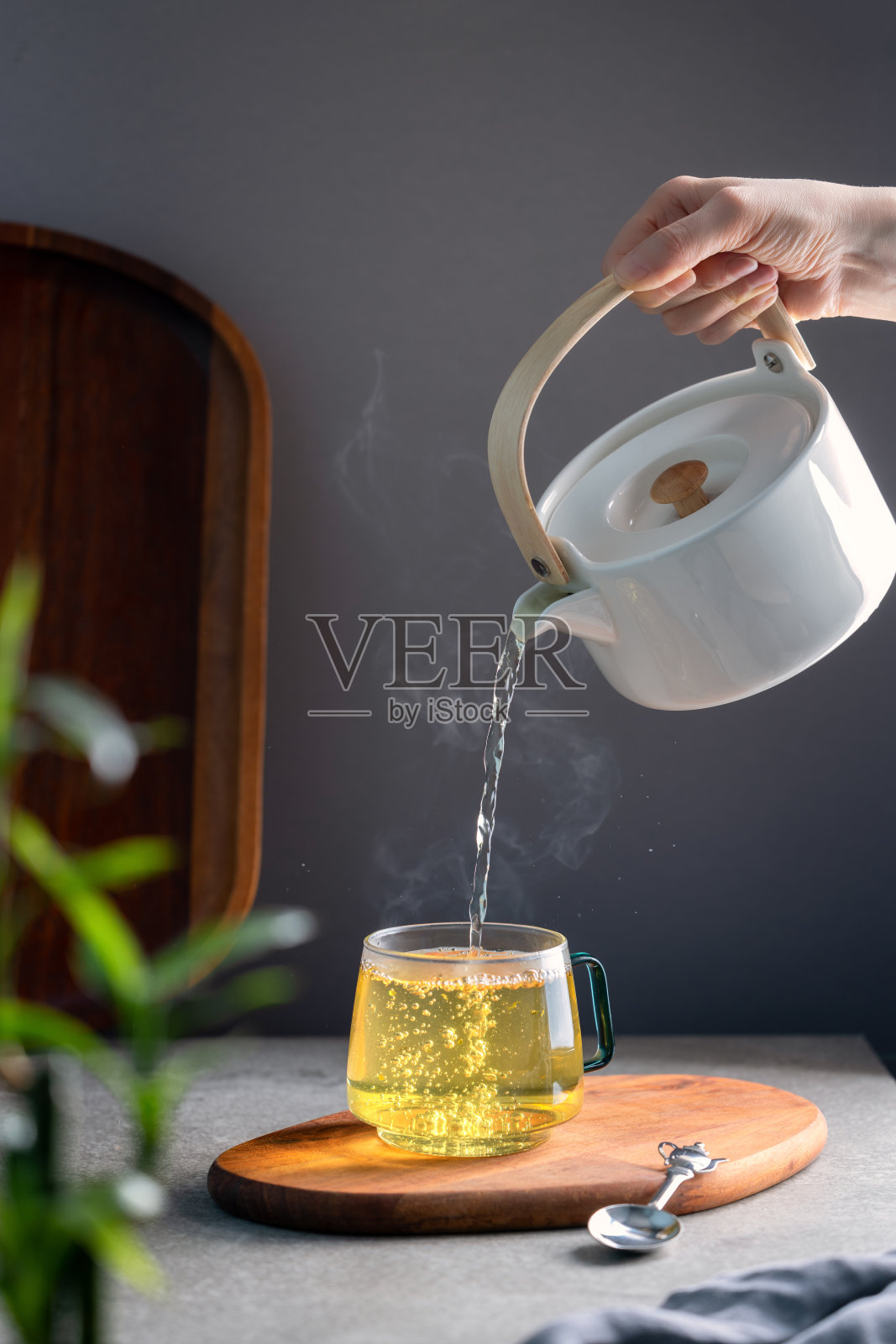 把热腾腾的绿茶倒进透明的杯子里照片摄影图片