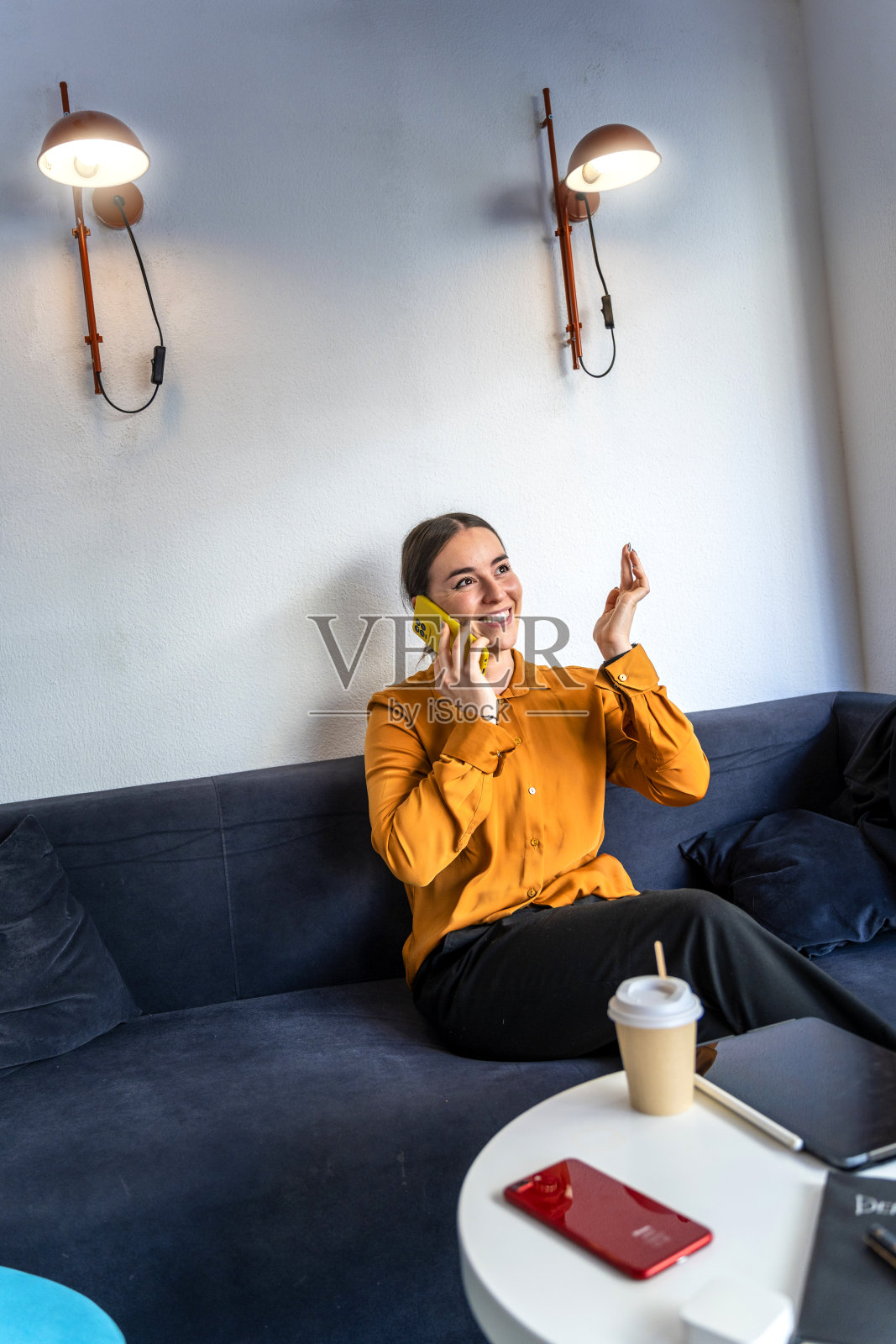 穿着橙色衬衫的时装设计师在打电话。照片摄影图片