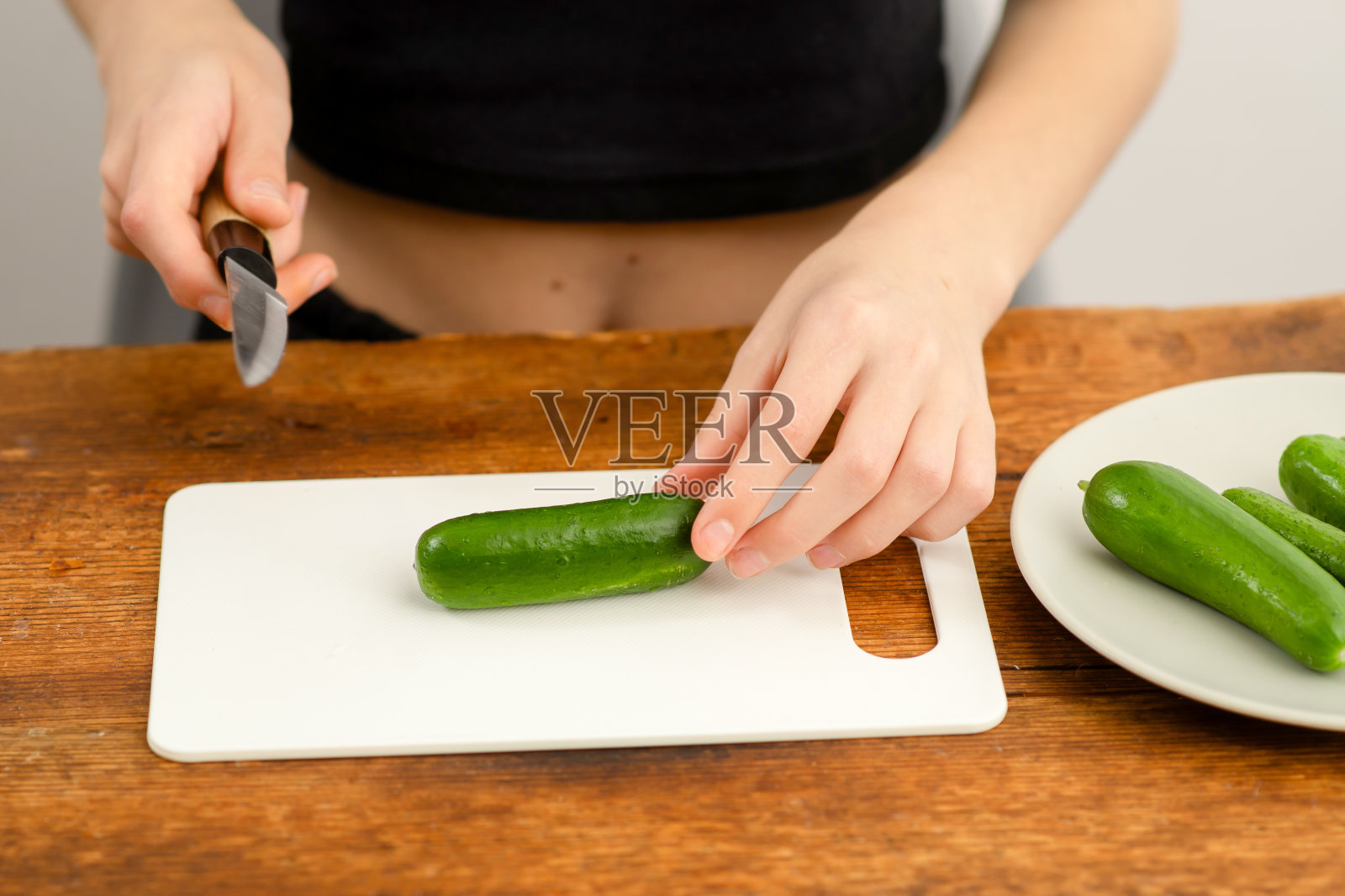 新鲜沙拉准备:女性双手在砧板上切绿黄瓜，拥抱沙拉制作的艺术和素食生活方式的好处照片摄影图片