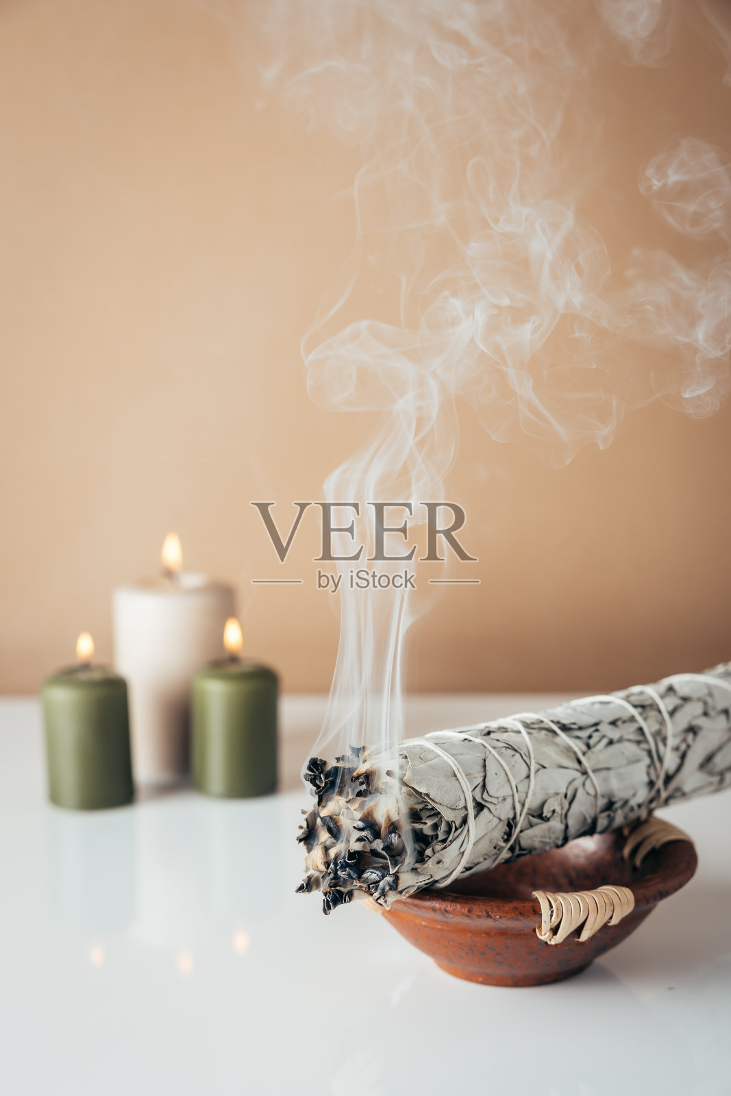 背景是白色的鼠尾草和燃烧的蜡烛照片摄影图片