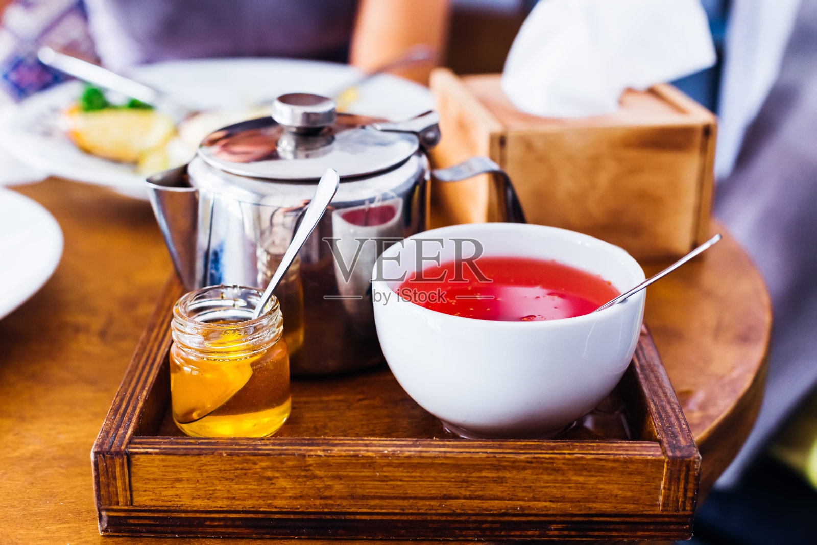 水果茶，蜂蜜和一个金属水壶放在一个漂亮的木制托盘上照片摄影图片