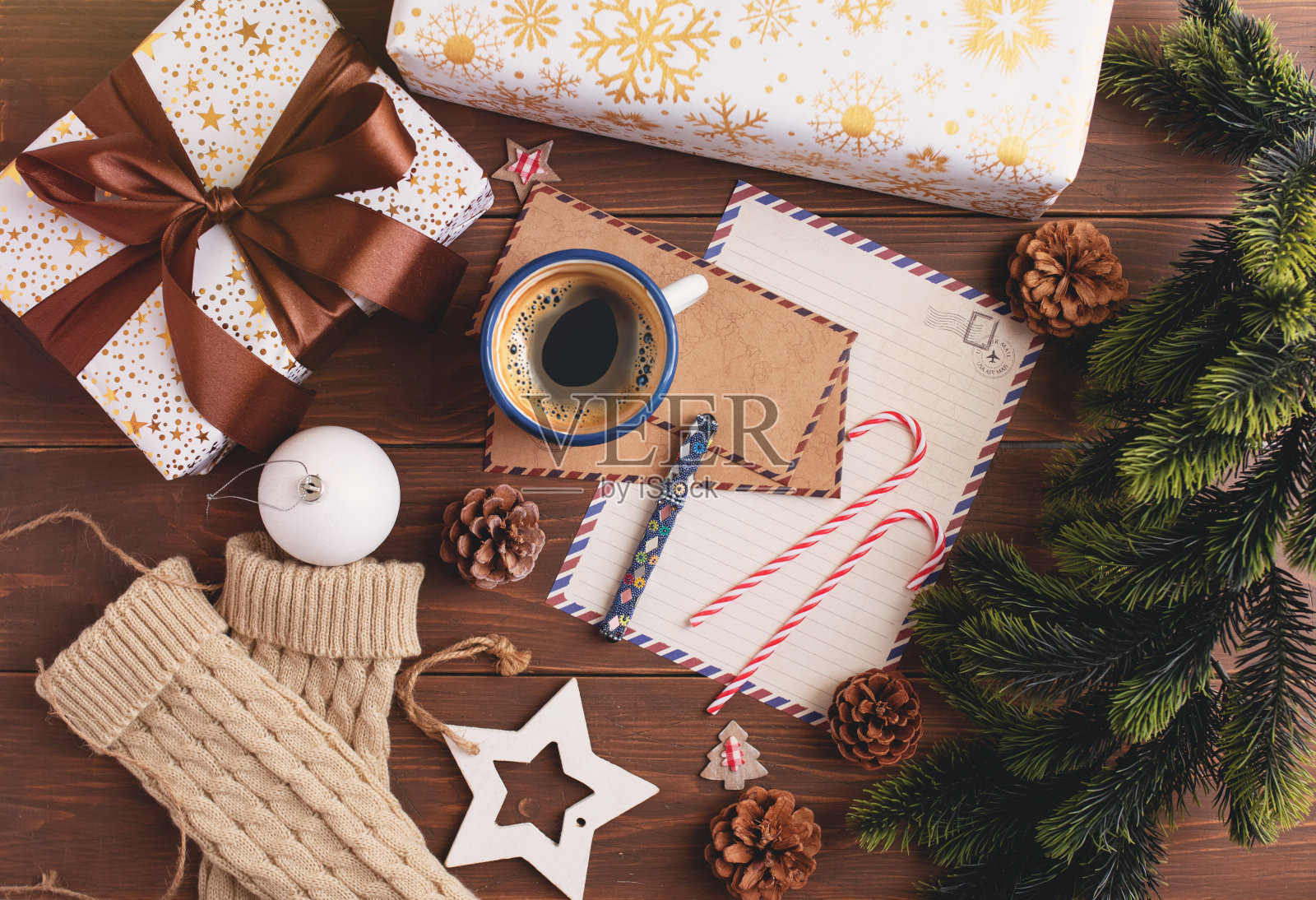 一个写圣诞信的笔记本，一个礼物包装，一棵雪树和一个咖啡杯。从上面看照片摄影图片