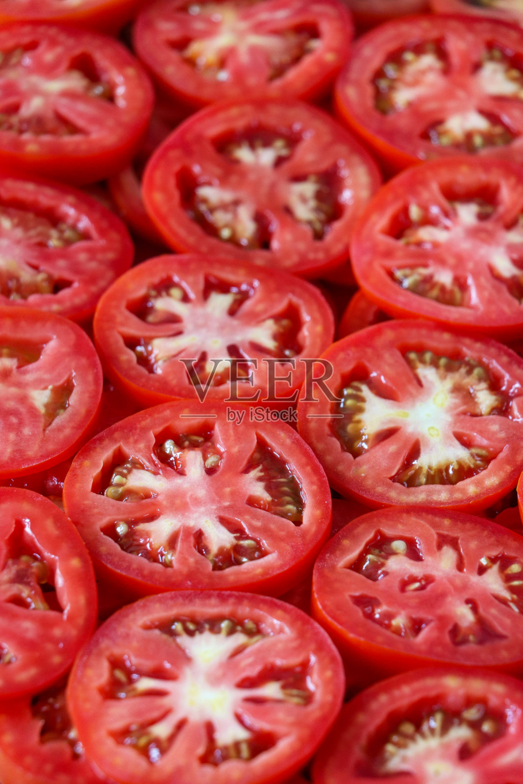 多层番茄片的全画幅图像显示薄皮，鲜红的果肉和种子，健康饮食海报壁纸背景设计，高架视图，重点放在前景照片摄影图片