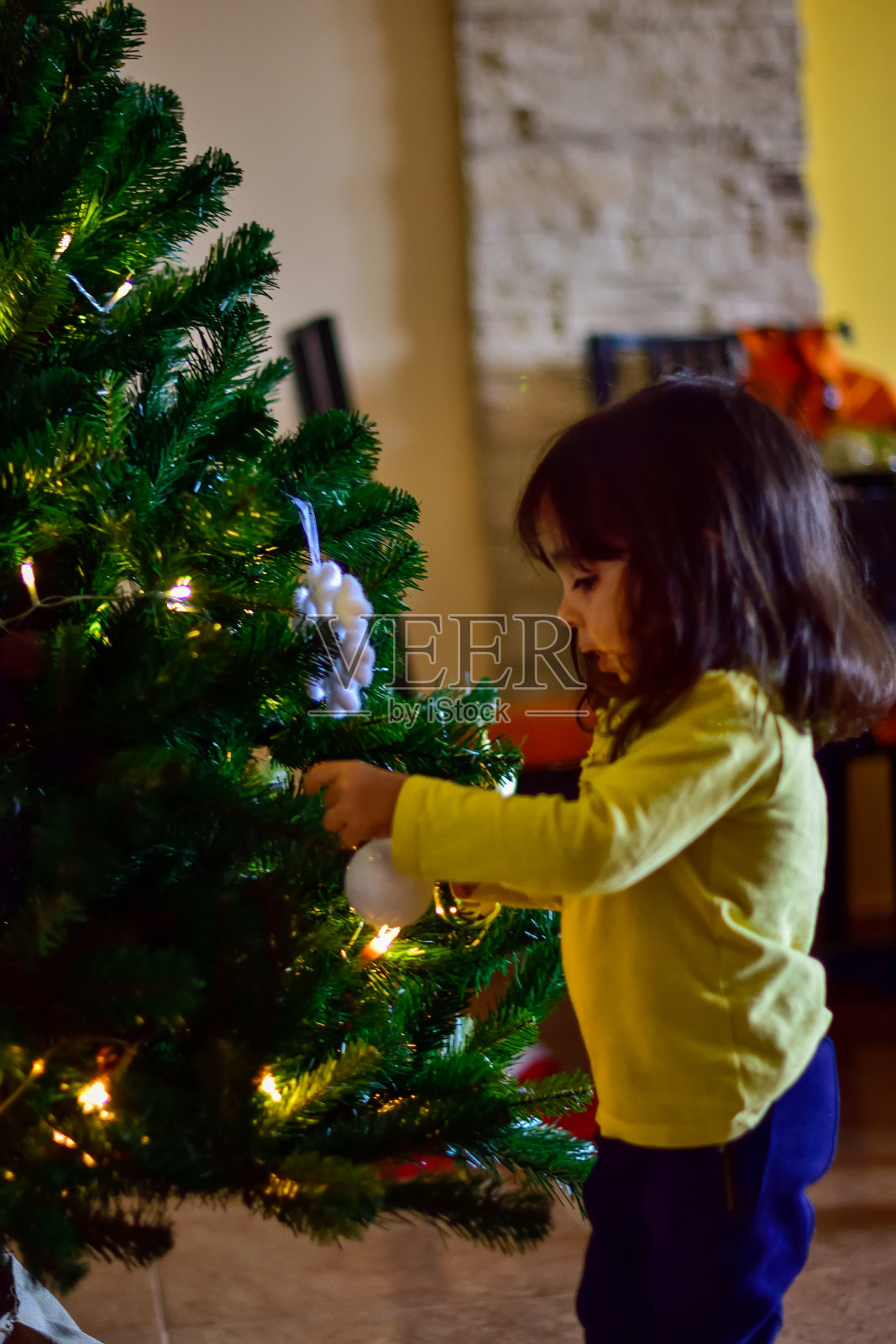 女孩把数字放在圣诞树上照片摄影图片