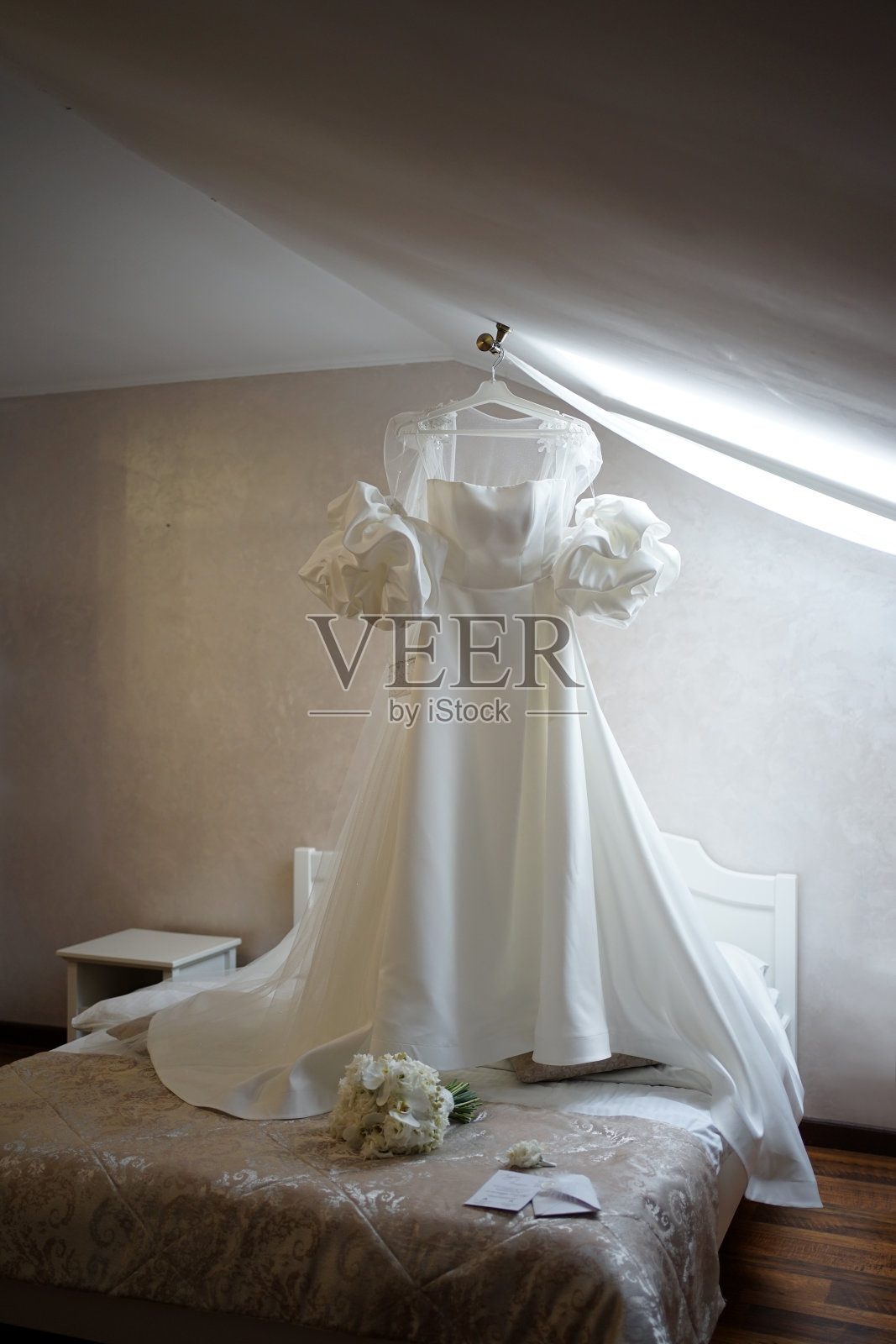 房间里挂着一件漂亮的白色婚纱。准备婚礼。照片摄影图片