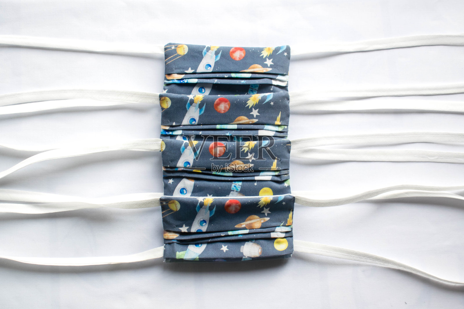 一堆手工制作的儿童口罩，可以保护他们免受Covid-19等传染病的侵害。100%纯棉，飞船印花。照片摄影图片