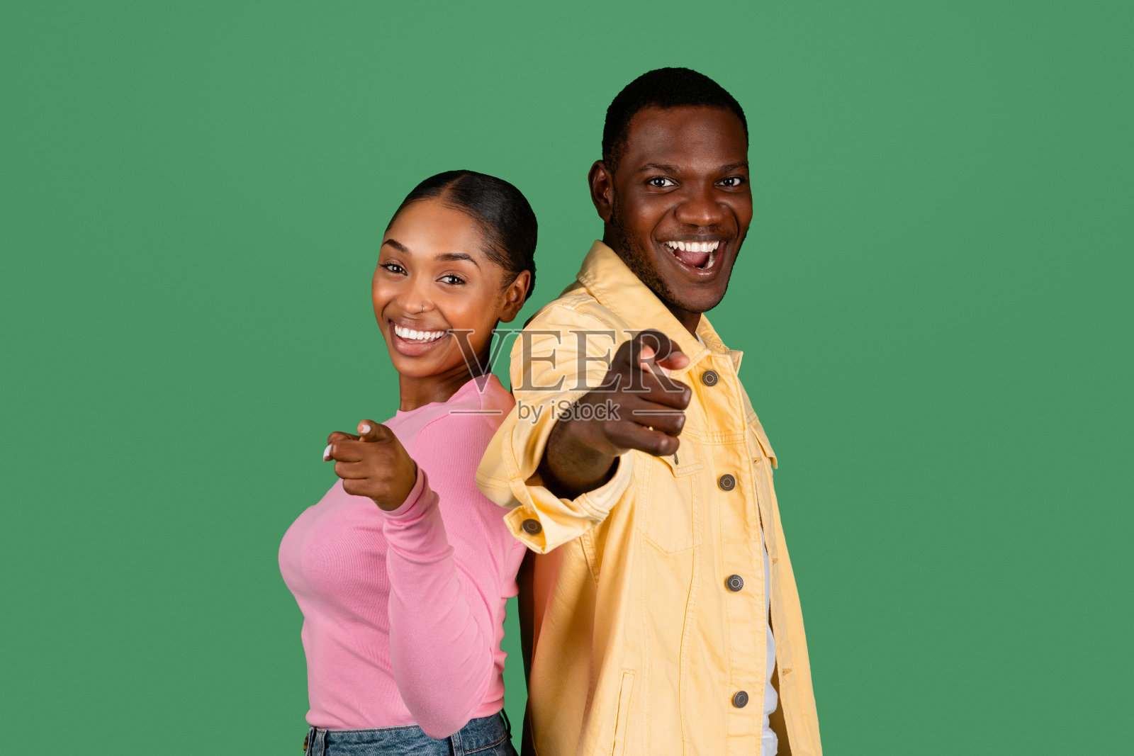 欢快的黑人夫妇指着相机，绿色背景照片摄影图片