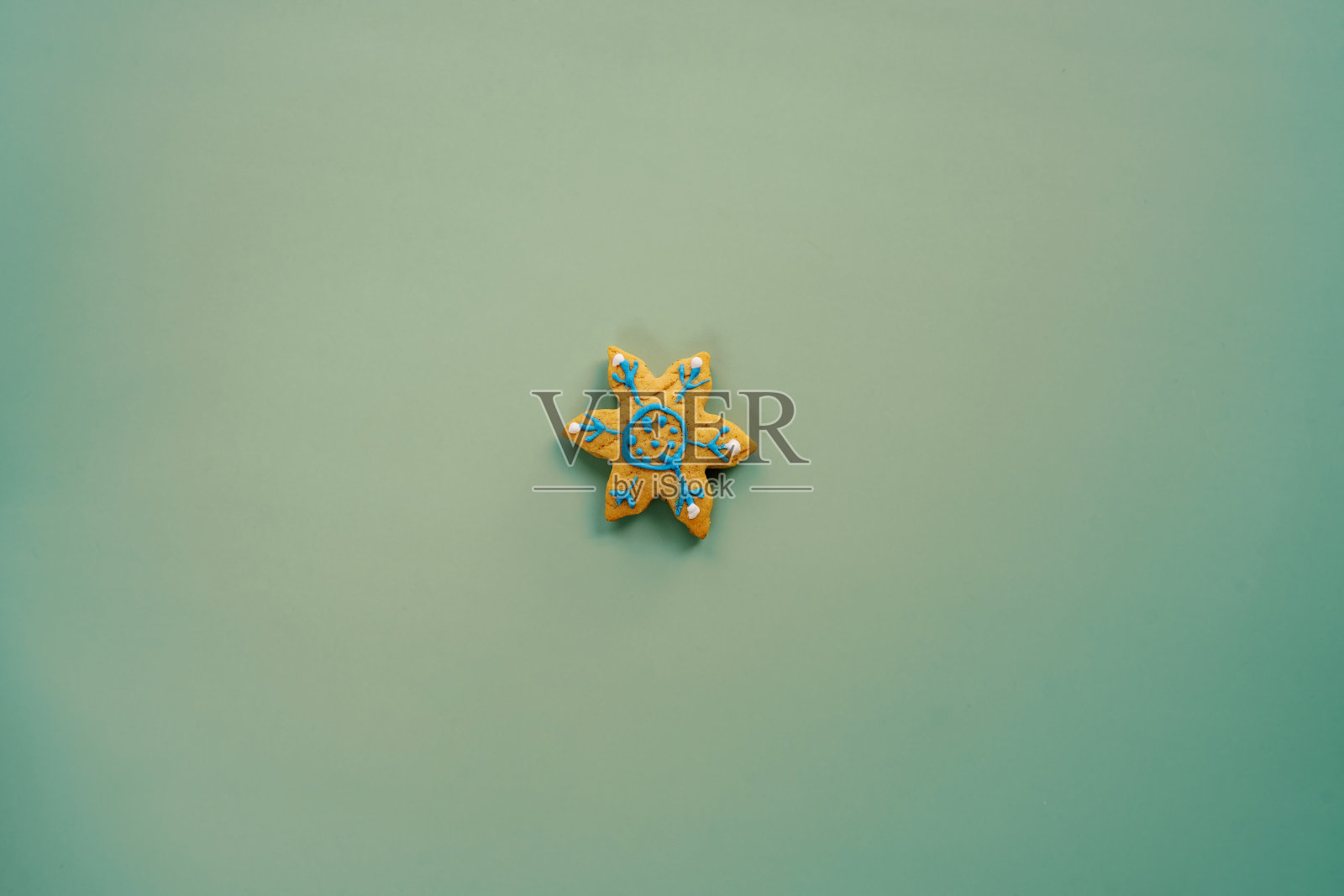 绿色的背景上点缀着雪花形状的光滑饼干照片摄影图片